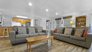A modern living room with two grey sofas, a wooden coffee table, and a kitchen in the background. - The Lift C112 (Breckenridge)