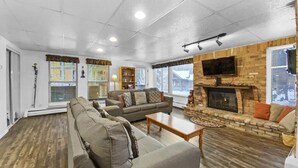 A living room with a fireplace, a sofa set, and a television mounted on the wall. - The Lift C112 (Breckenridge)