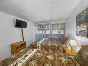 A bedroom with two beds, a TV on the wall, and a poster on the wall. - The Lift C112 (Breckenridge)