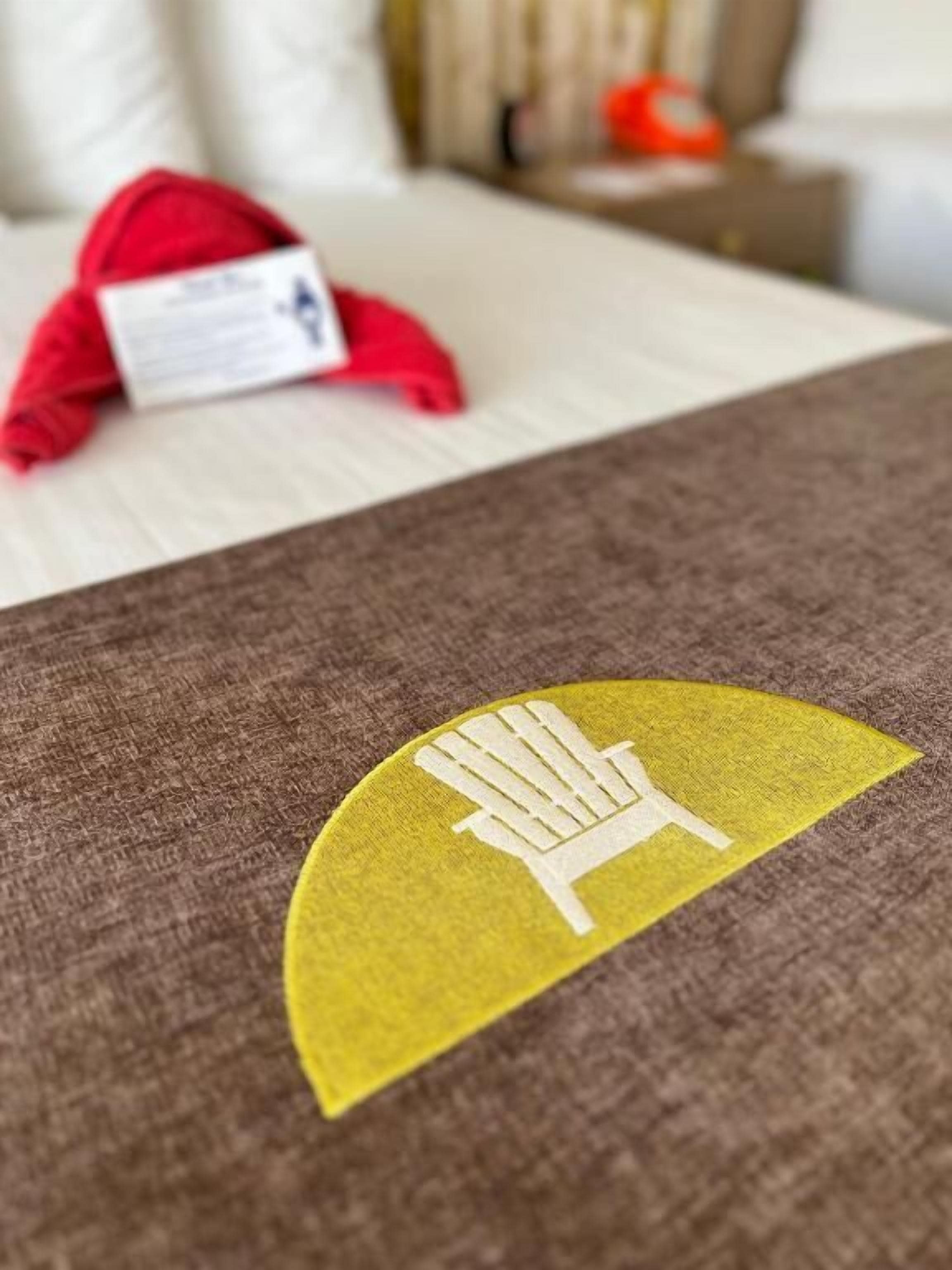 Un lit recouvert d’une couverture marron ornée d’un motif jaune.