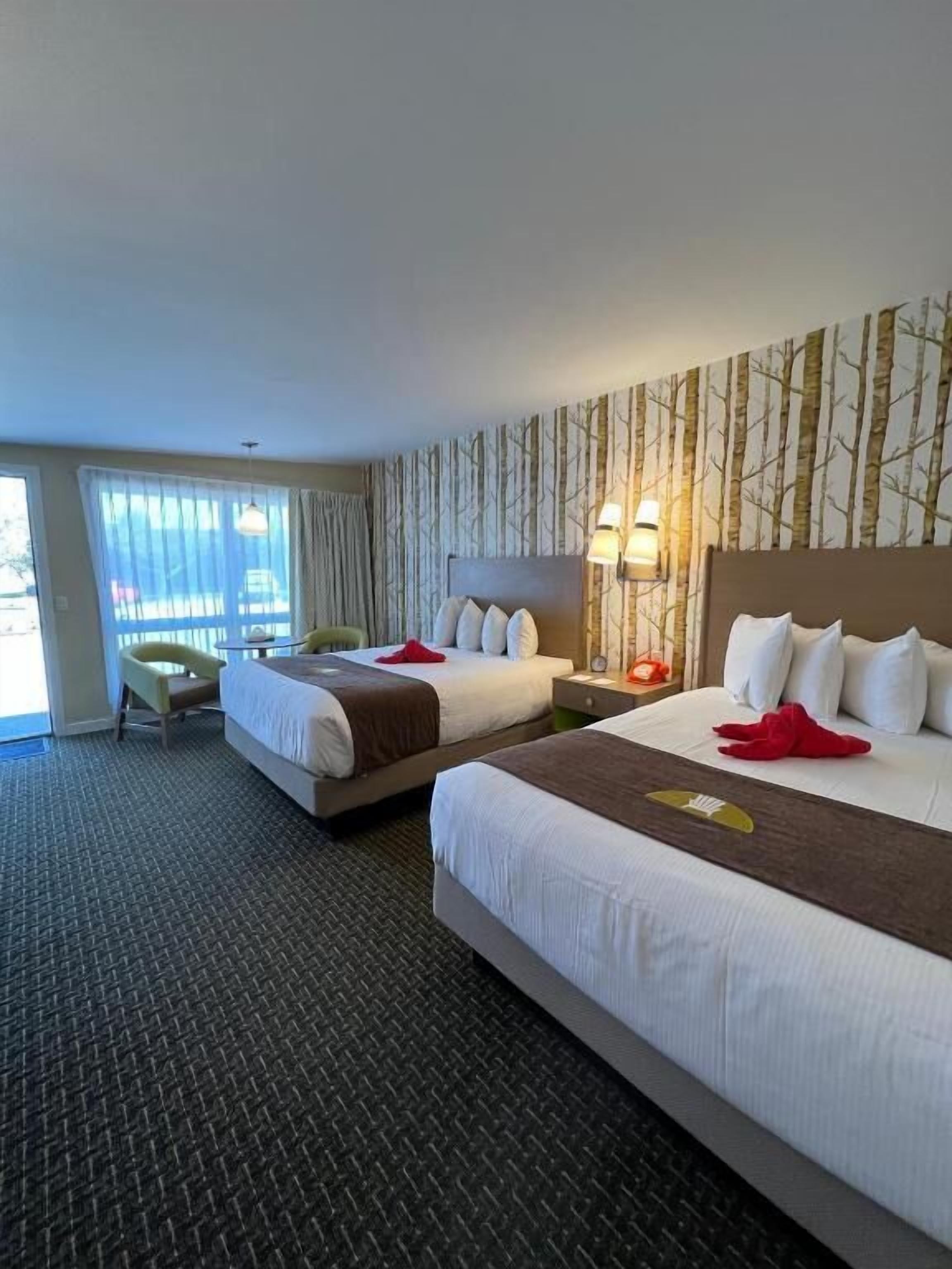 Une chambre d’hôtel avec deux lits, un bureau et une chaise.