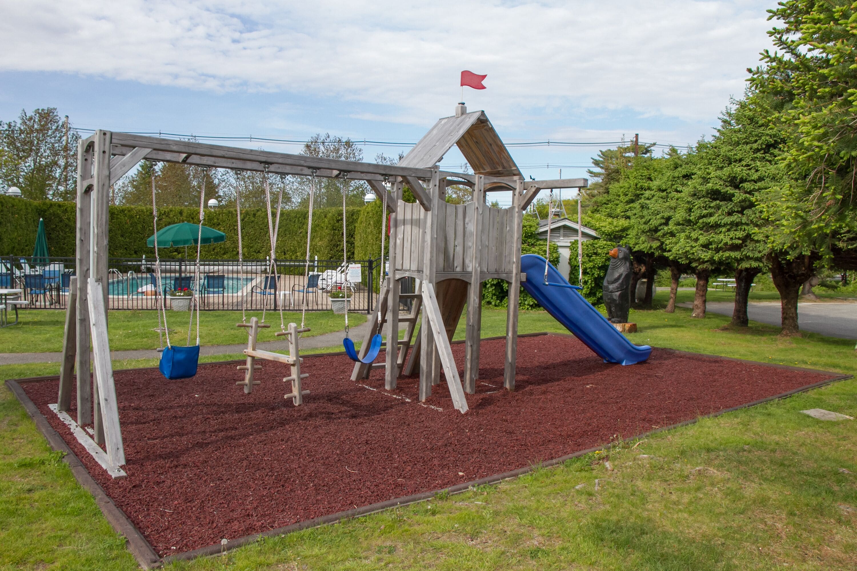 A playground with a swing set, slide, and climbing structure.