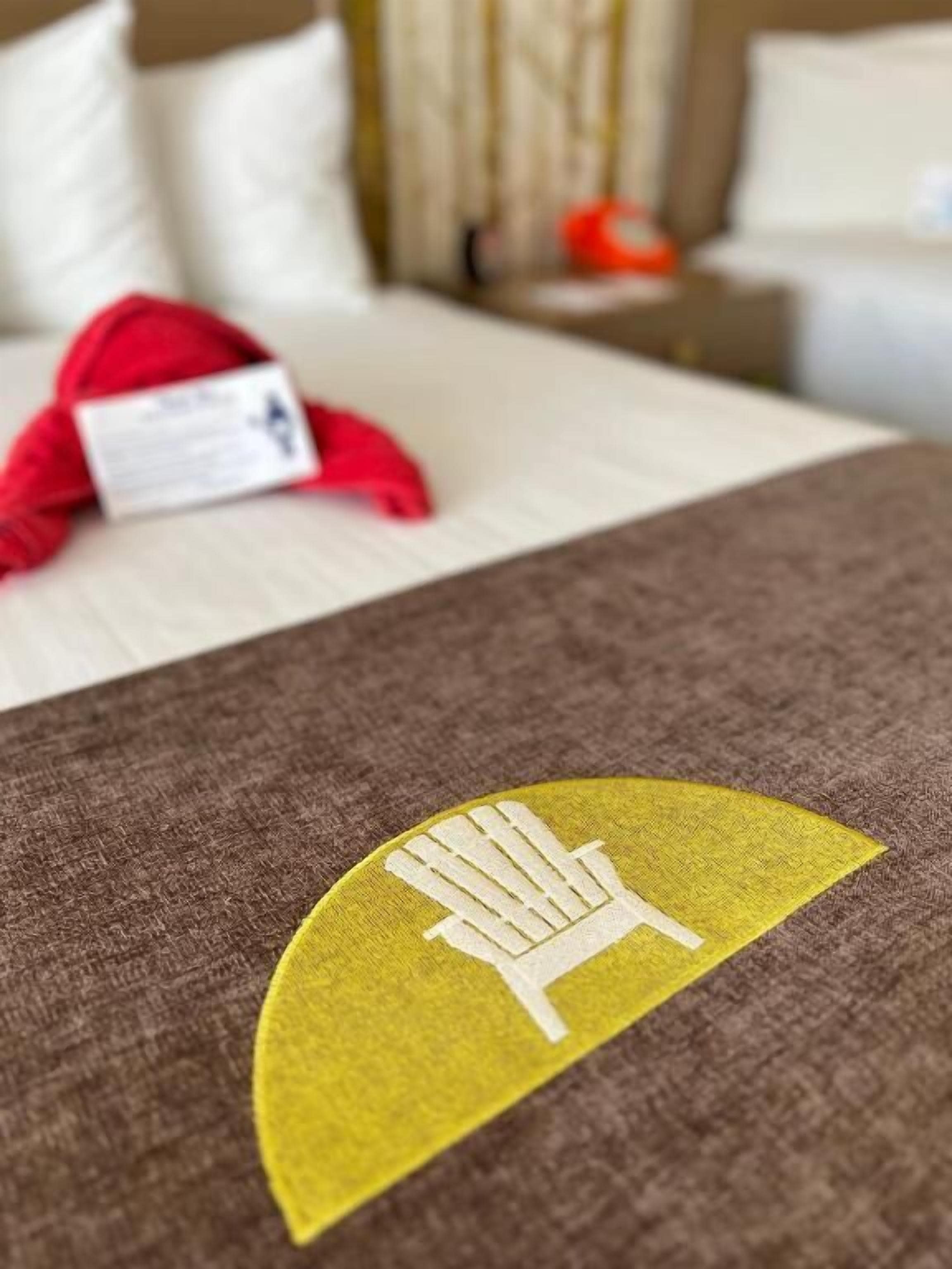 A bed with a brown cover and a logo on it.