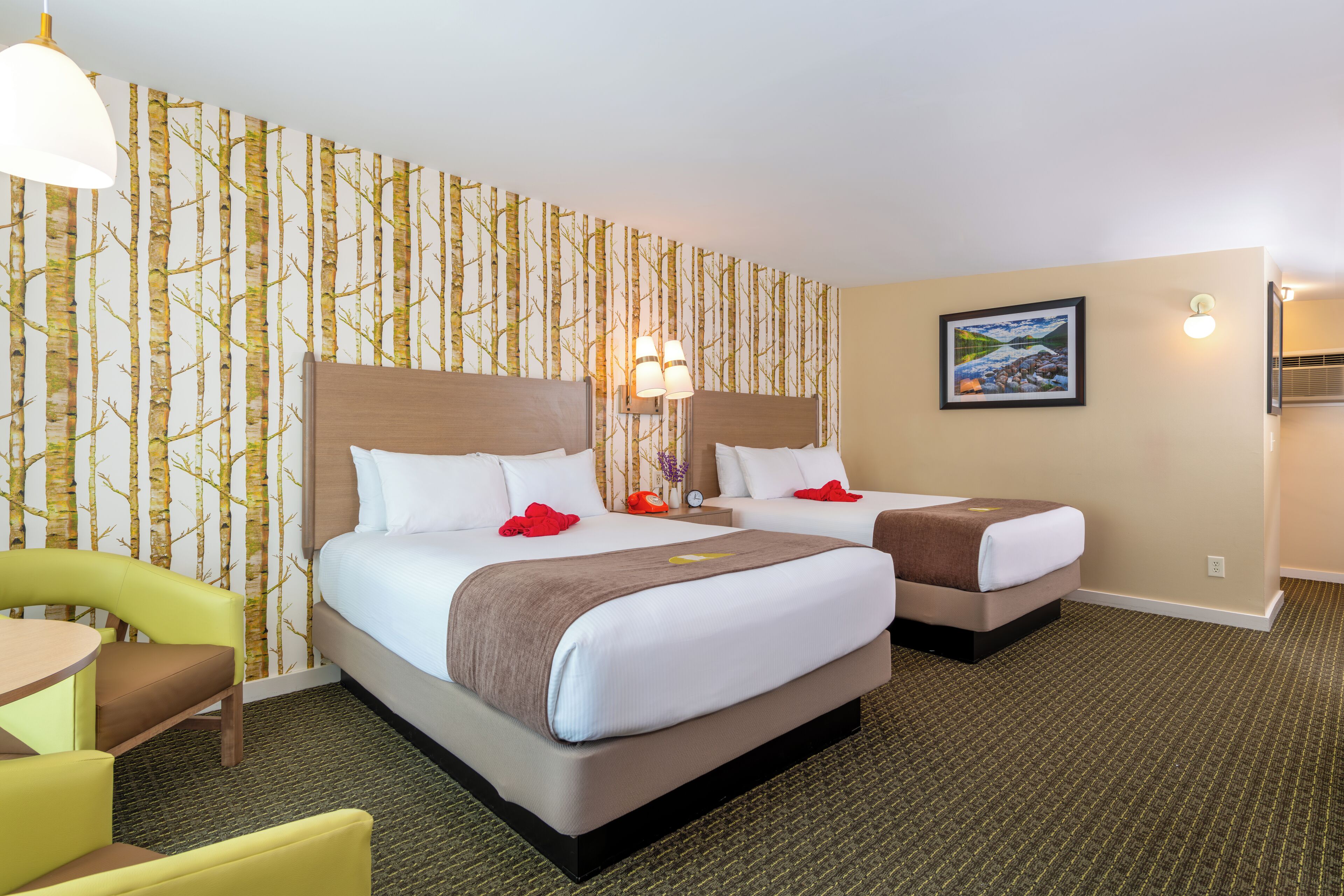 A hotel room with two beds, a small table, and a chair.