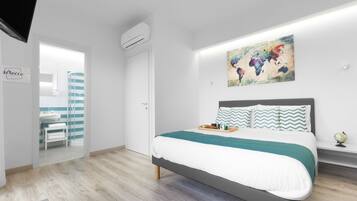 Quarto moderno com cama, uma obra de arte com um mapa-múndi e um banheiro visível através de uma porta aberta.