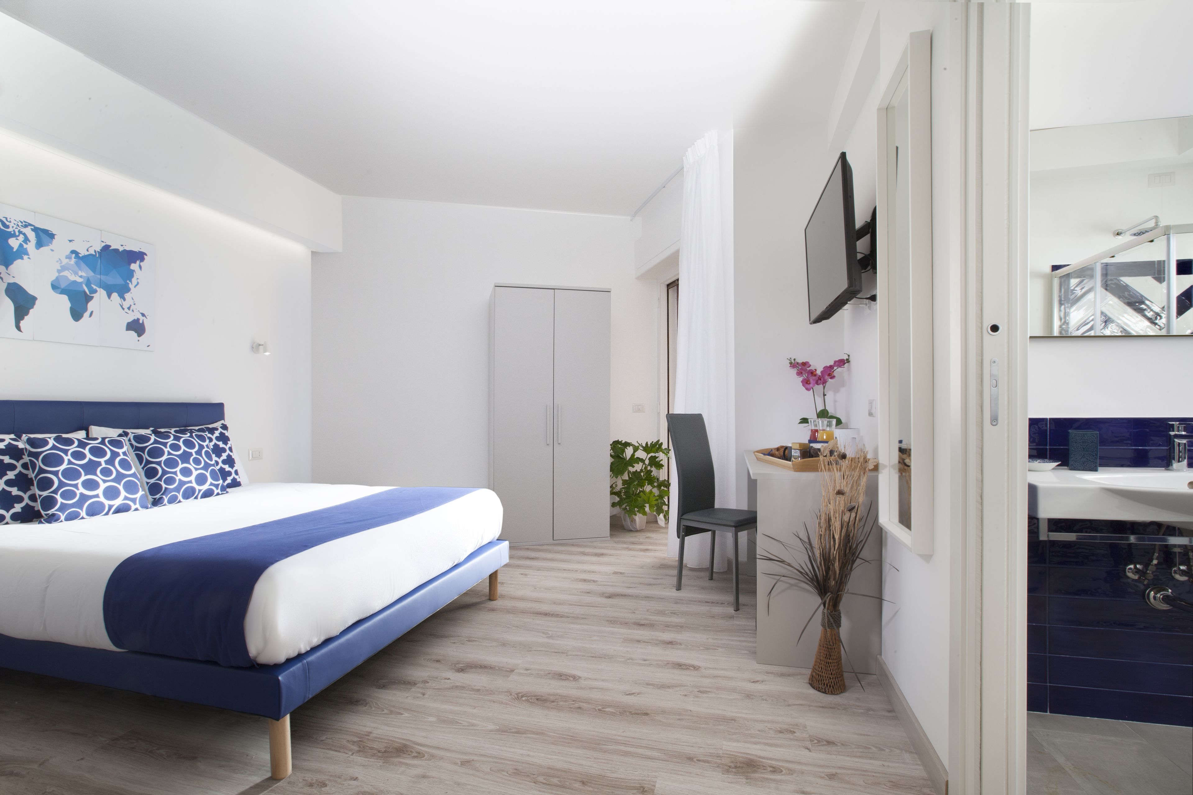 A modern bedroom with a bed, a desk, and a bathroom.
