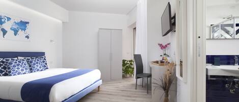 A modern bedroom with a bed, a desk, and a bathroom.