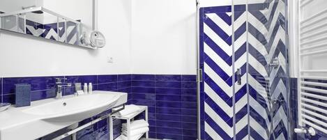 A modern bathroom with a large sink, mirror, and shower area.