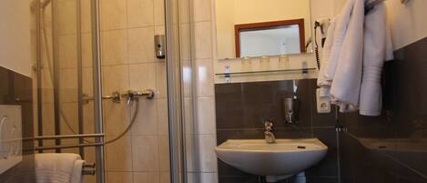 Un baño con ducha de vidrio, lavamanos e inodoro.