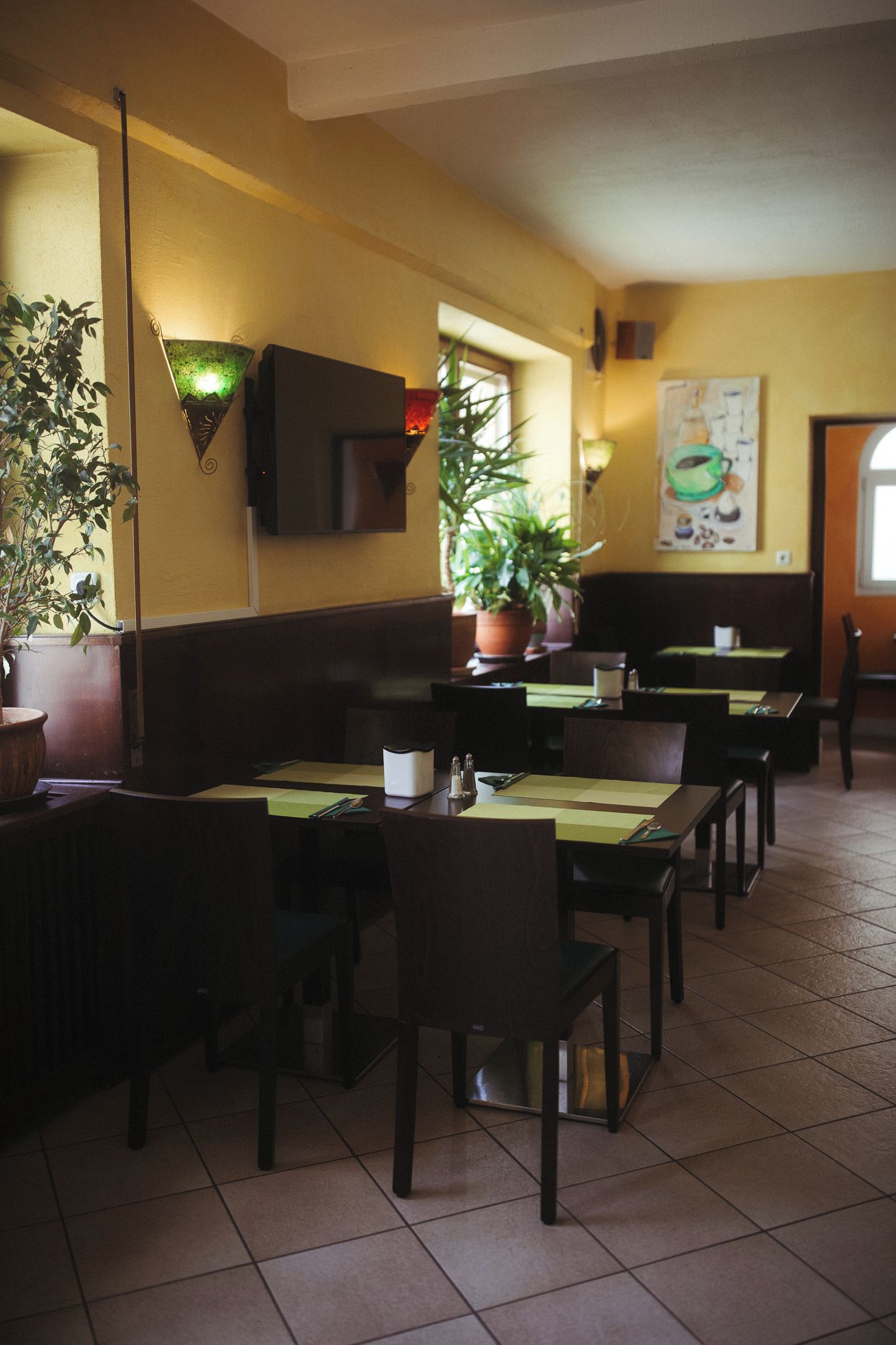 Ein Restaurantinneres mit Sitzecken, Tischen und Blumentöpfen.