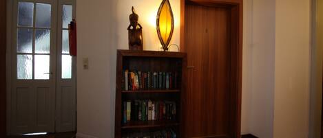 Un pasillo con una estantería de madera, una puerta y un adorno iluminado en la pared.