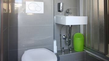 Un baño moderno con inodoro blanco, lavamanos y zona de ducha.