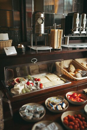 Un área de bufé con una variedad de alimentos, incluyendo queso, frutas y pan.
