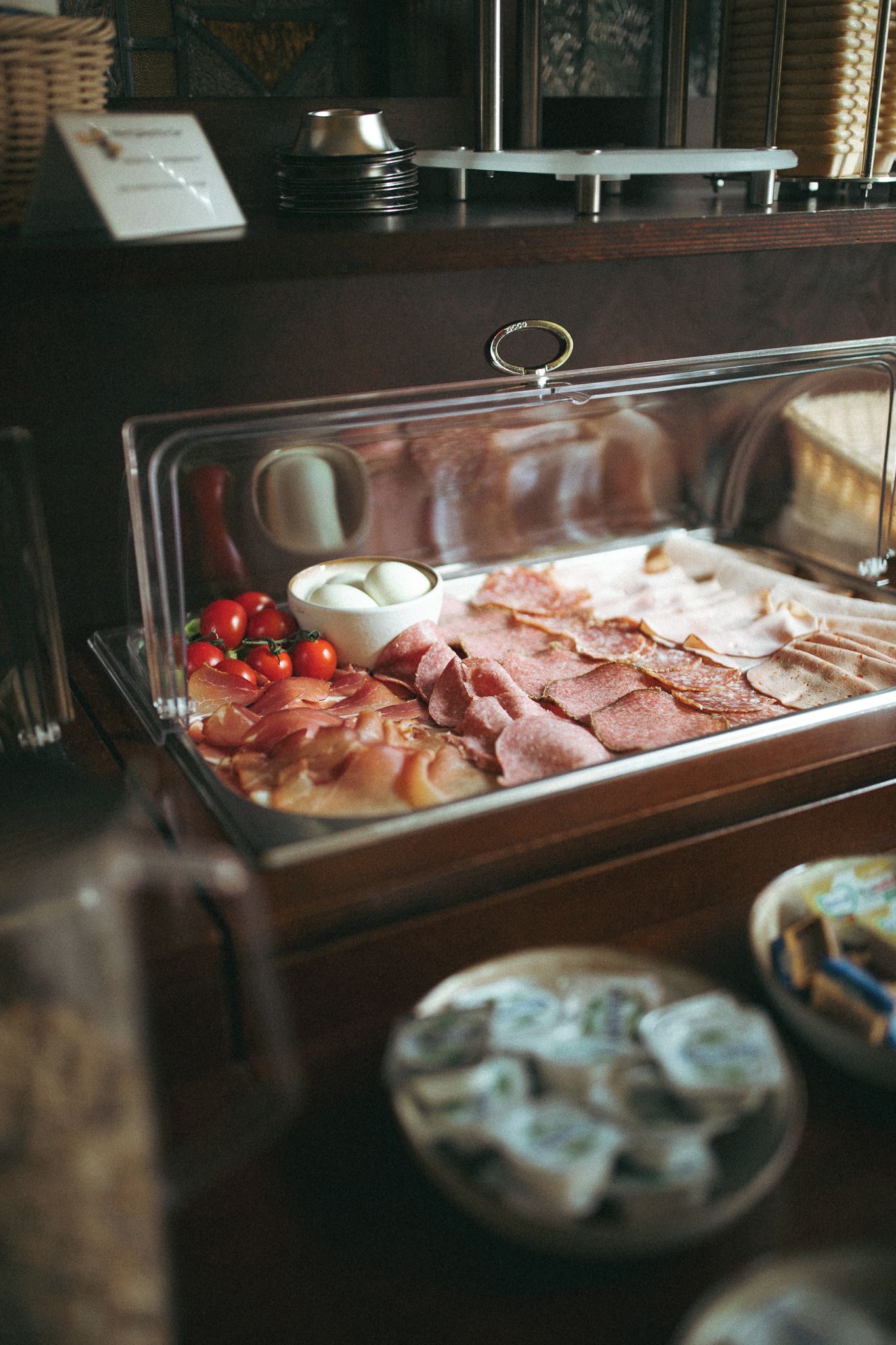 Een buffet met diverse etenswaren, waaronder vlees, kazen en een schaal eieren.