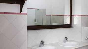 Casa de banho com duas pias, um espelho e um candeeiro no teto.