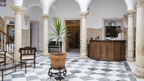 Un vestíbulo con piso a cuadros, un mostrador de recepción, un banco y una planta en maceta.
