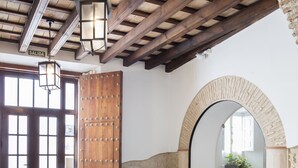 Un interior rústico con suelo de piedra, puerta de madera y espejo abovedado.