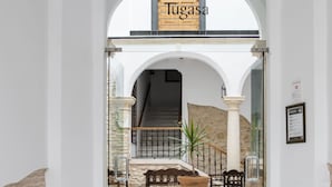 Entrada de un hotel con suelo de baldosas, una escalera y vista al interior.