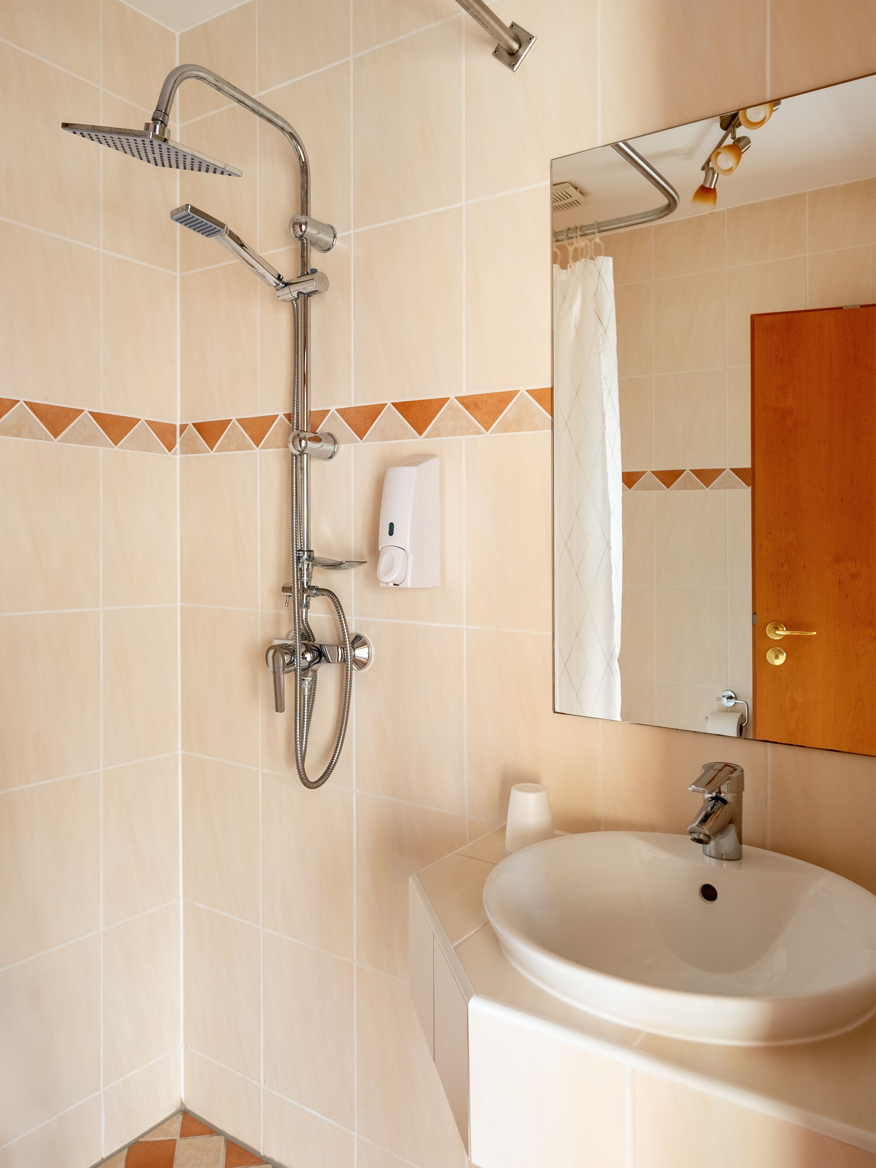A bathroom with a shower, a sink, and a mirror.