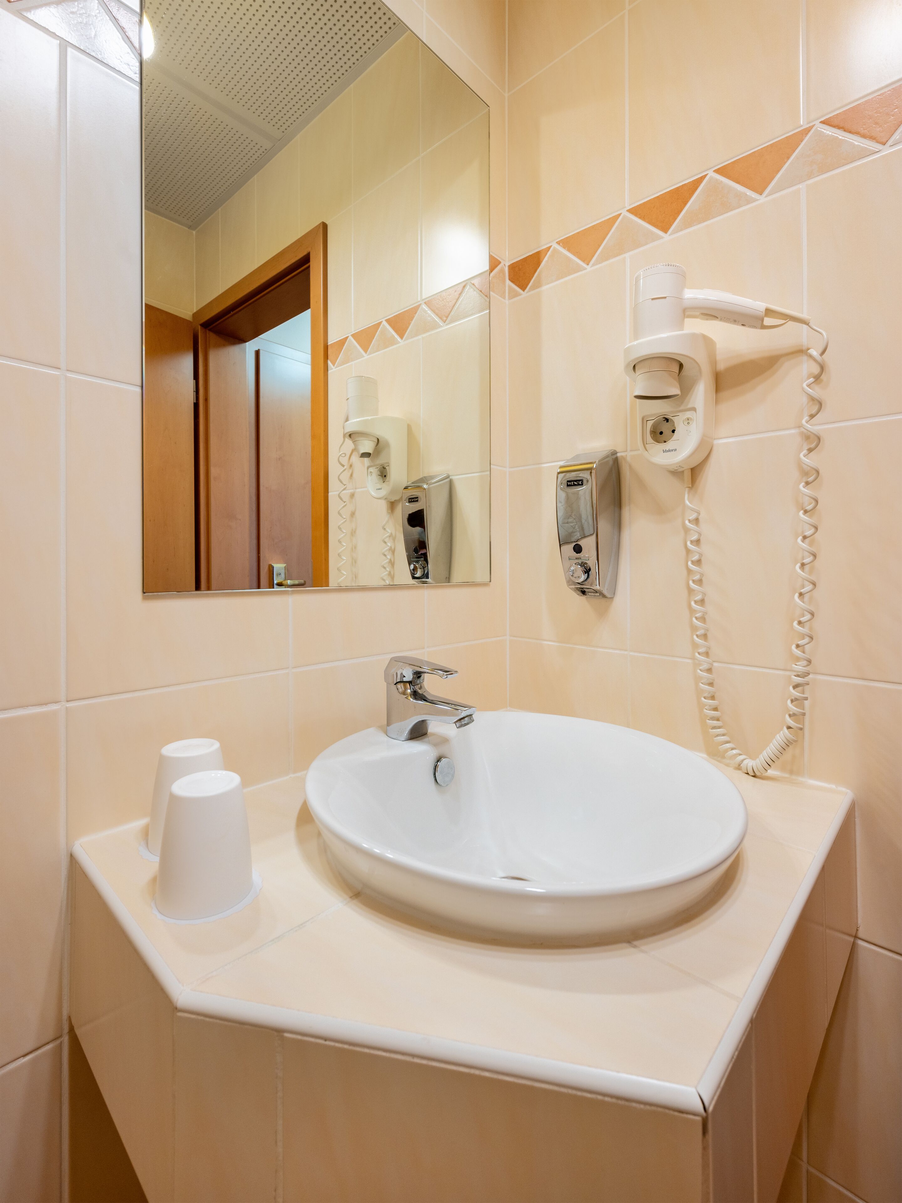 A bathroom with a sink, mirror, and hairdryer.