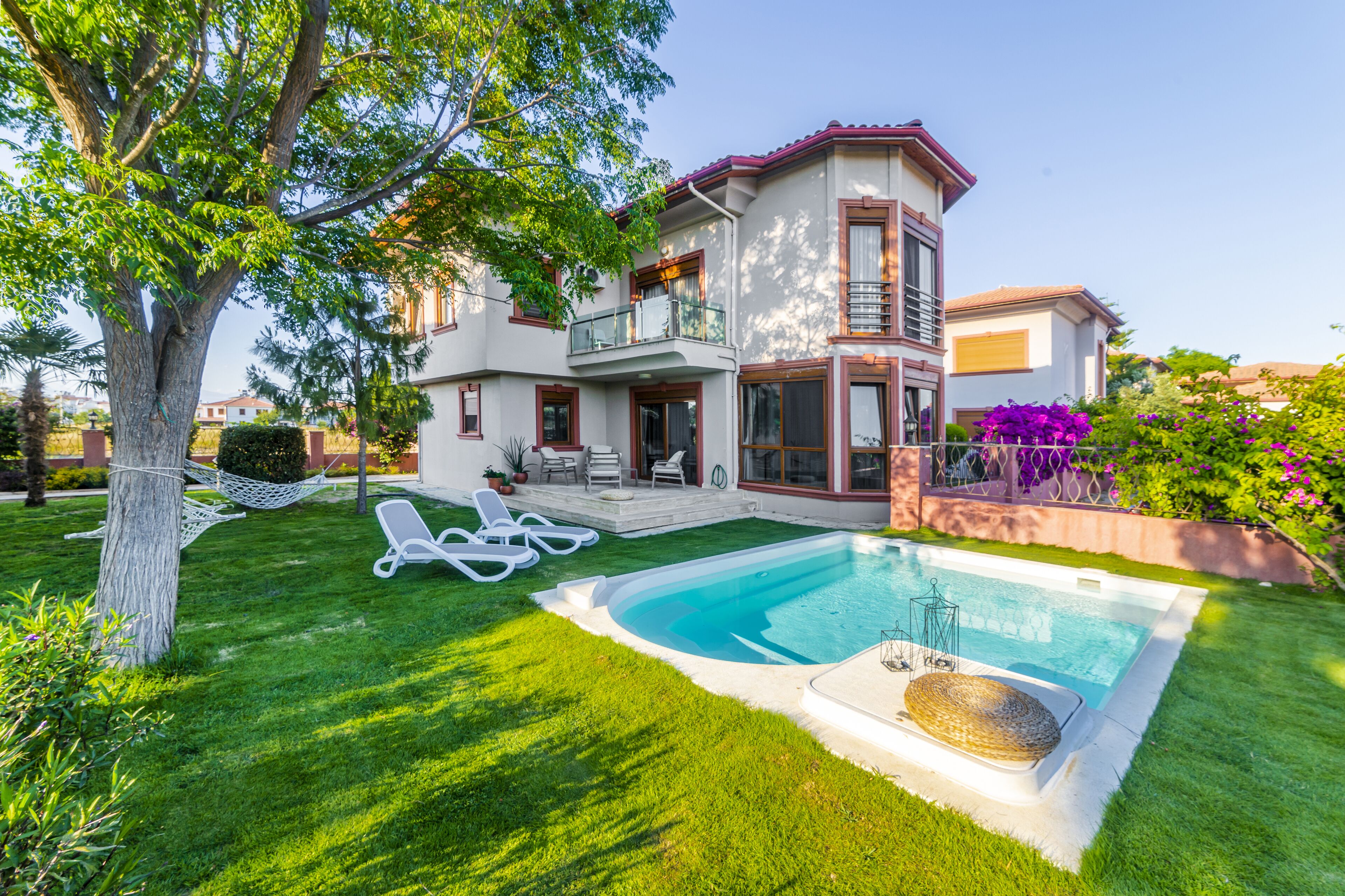 Ein zweistöckiges Haus mit Swimmingpool, einer Hängematte und Gartenmöbeln.