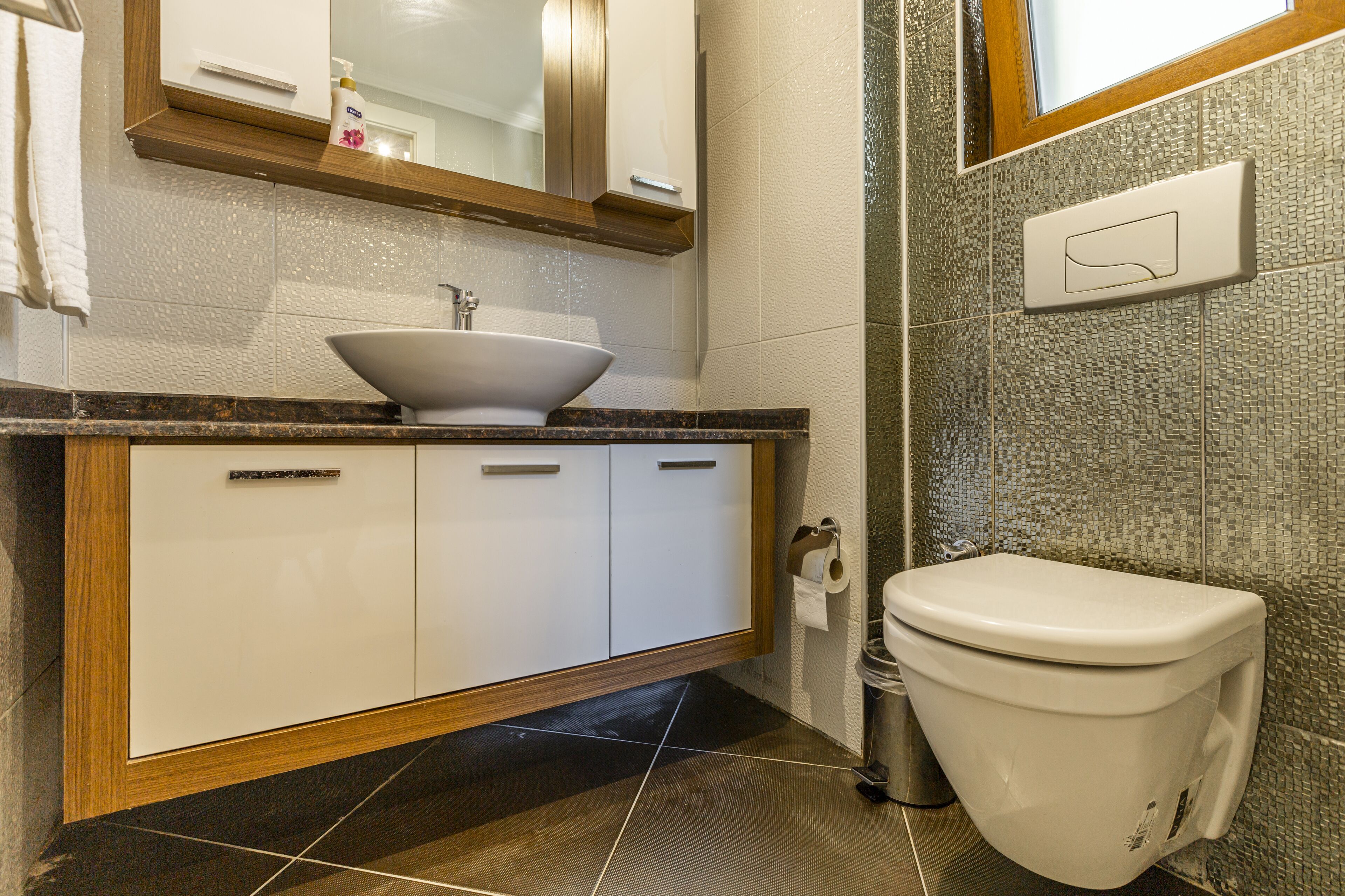 A bathroom with a white sink, a toilet, and a mirror above the sink.
