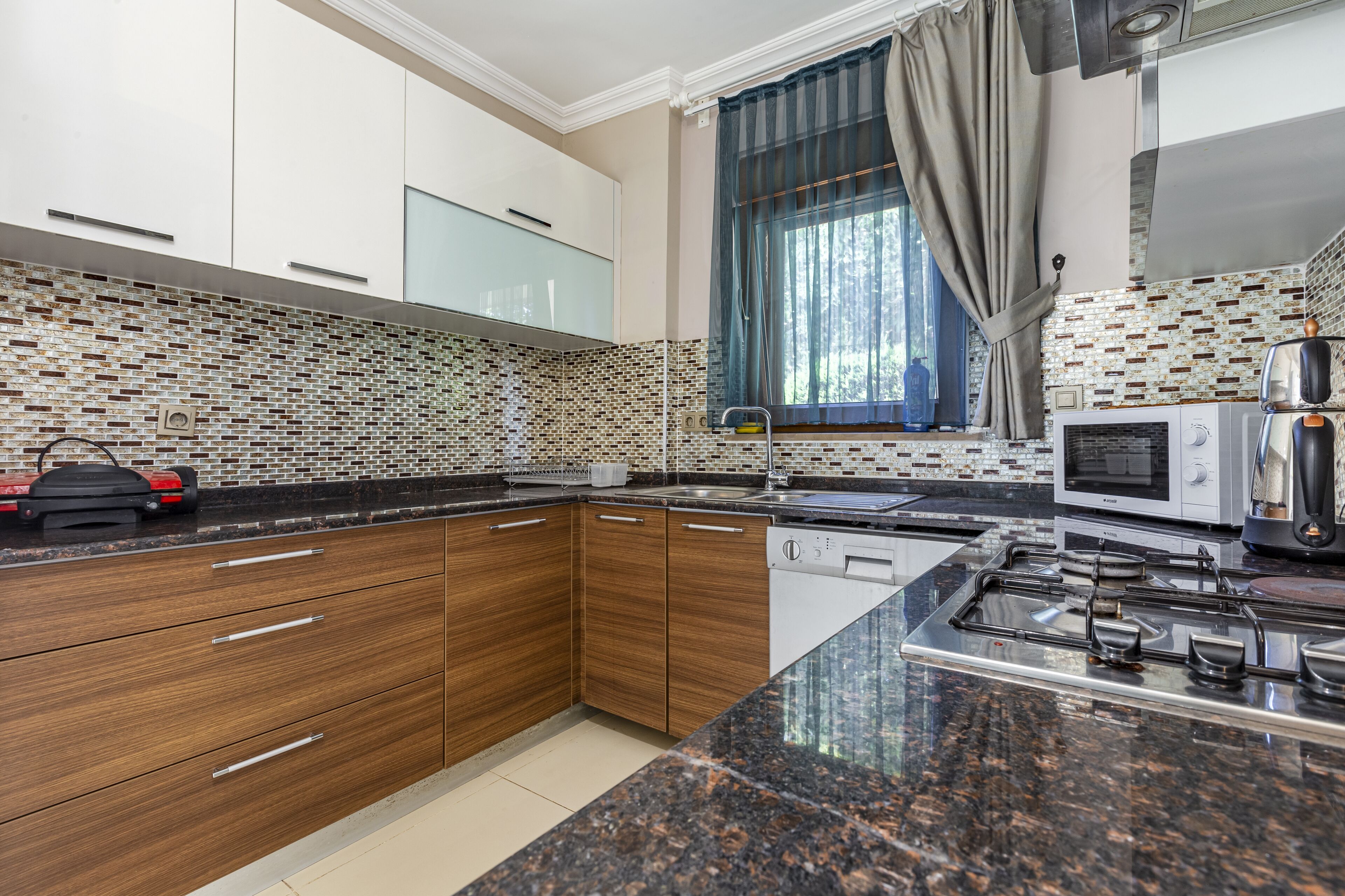 A modern kitchen with wooden cabinets, a granite countertop, a built-in microwave, and a gas stove.