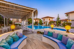 A poolside area with lounge chairs, a covered seating area, and a pool. - Vista Villas & Suites (Serik)