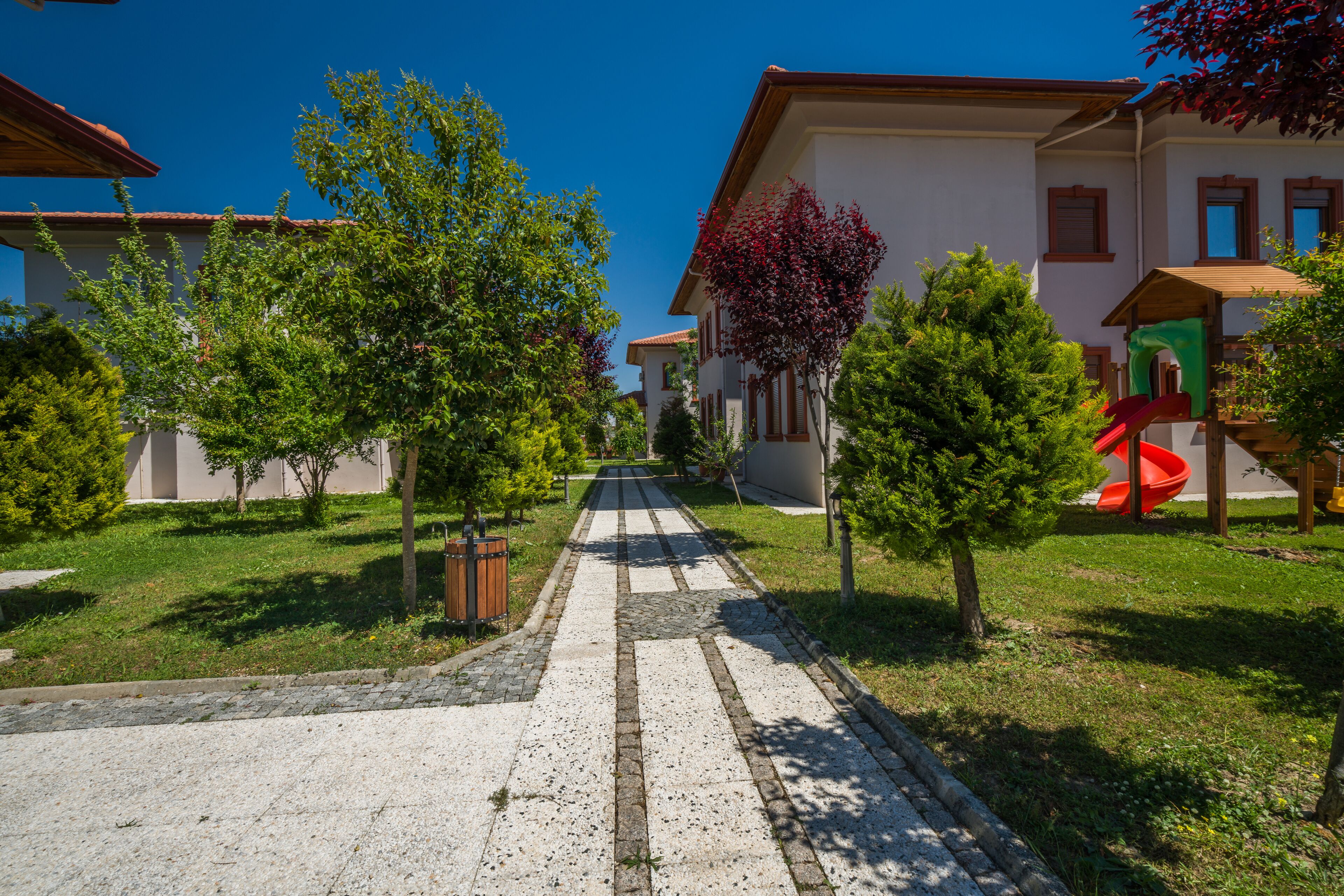 A residential street with houses, a playground, and a clear sky.