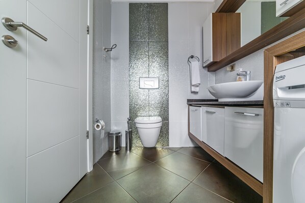 Un baño moderno con inodoro, lavamanos y armarios para guardar.