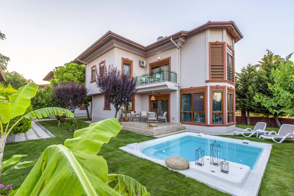 A two-story house with a swimming pool, a balcony, and a garden.