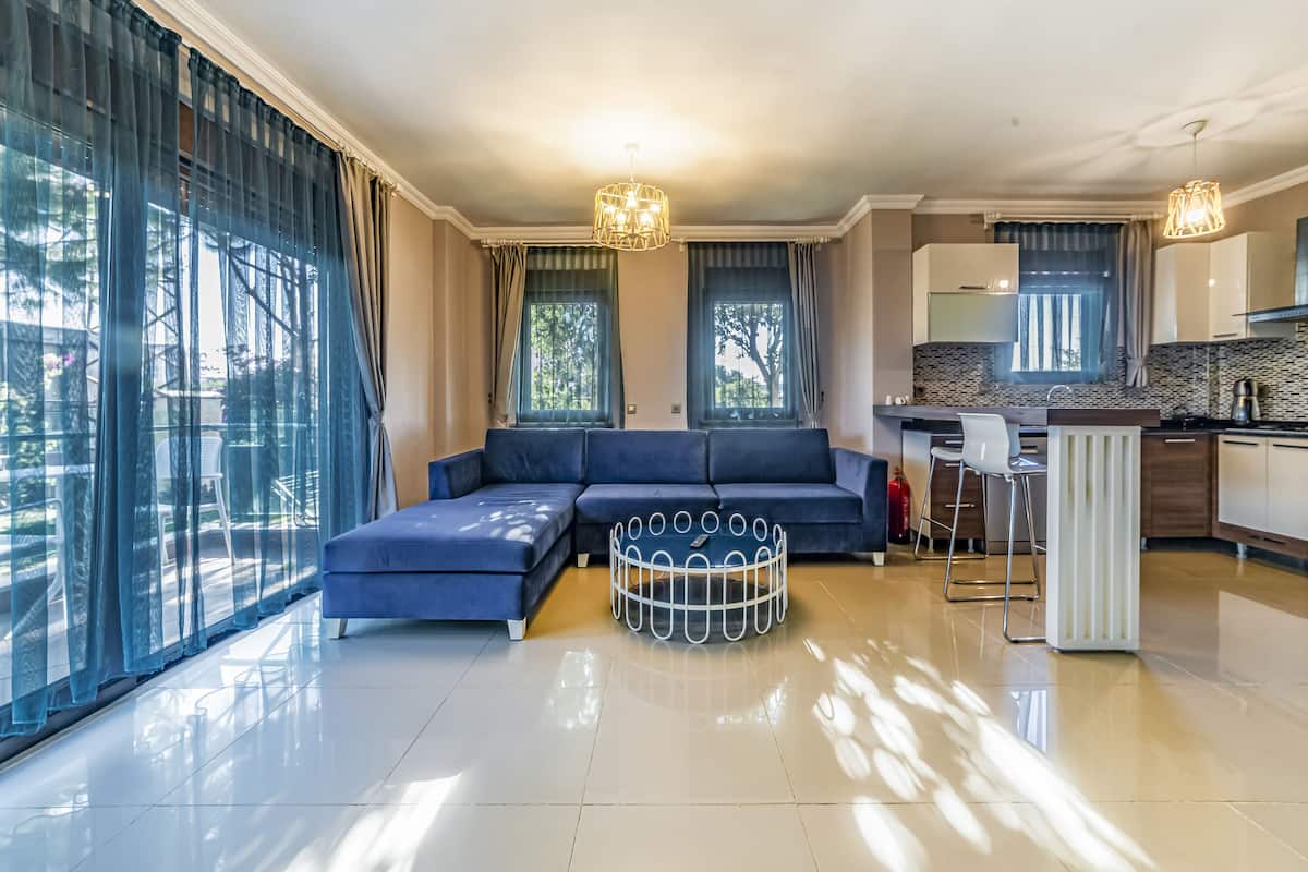 A modern living room with a sectional sofa, a round coffee table, and a kitchen area with a bar counter.