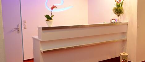 Un mostrador de recepción de diseño moderno, una planta en maceta y un objeto decorativo en la encimera.