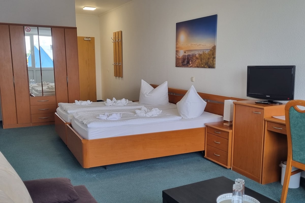 Un cuarto de hotel con cama, escritorio, televisor y vistas al exterior.