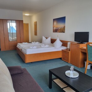 A hotel room with a bed, a desk, a television, and a view of the outdoors. - Müritz-Pension Waren (Waren (Müritz))