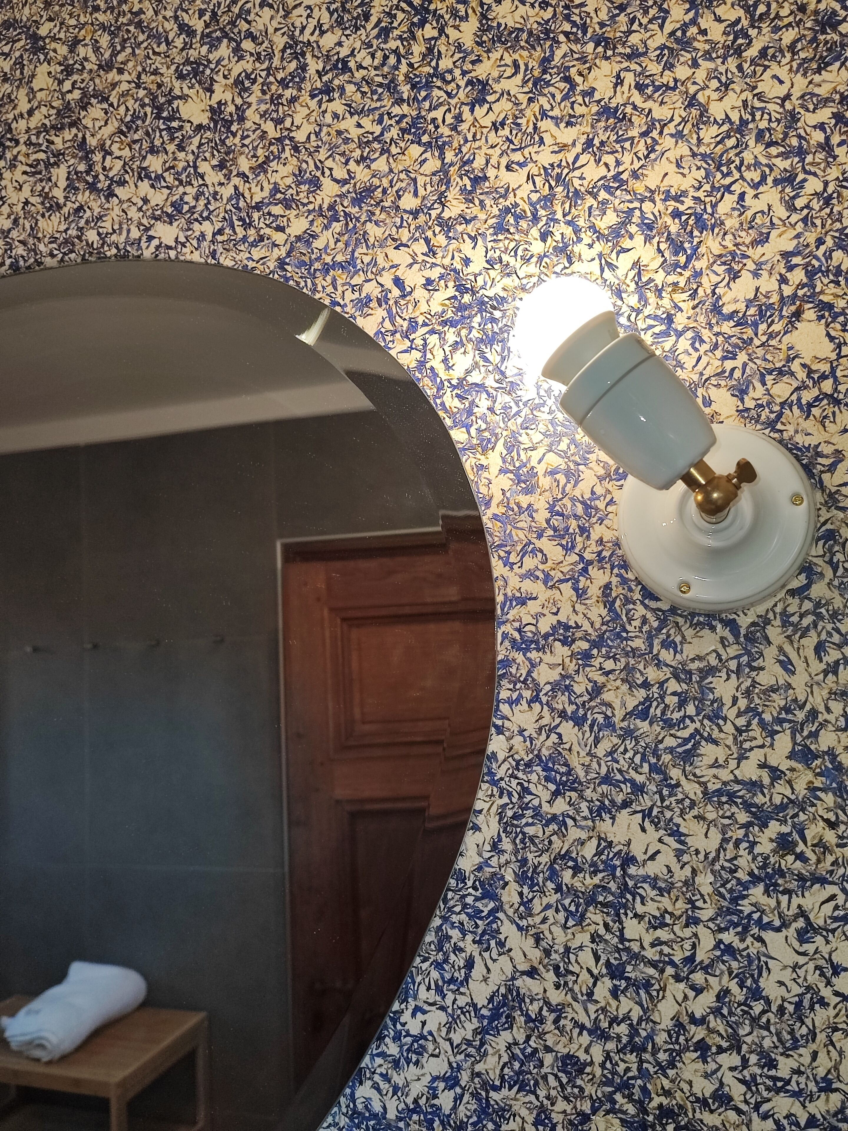 Ein Badezimmer mit Holztür, Handtuch auf einem kleinen Tisch und einer Wandleuchte.