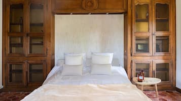 A bedroom with a large bed, wooden cabinets, and a small table with a bottle.