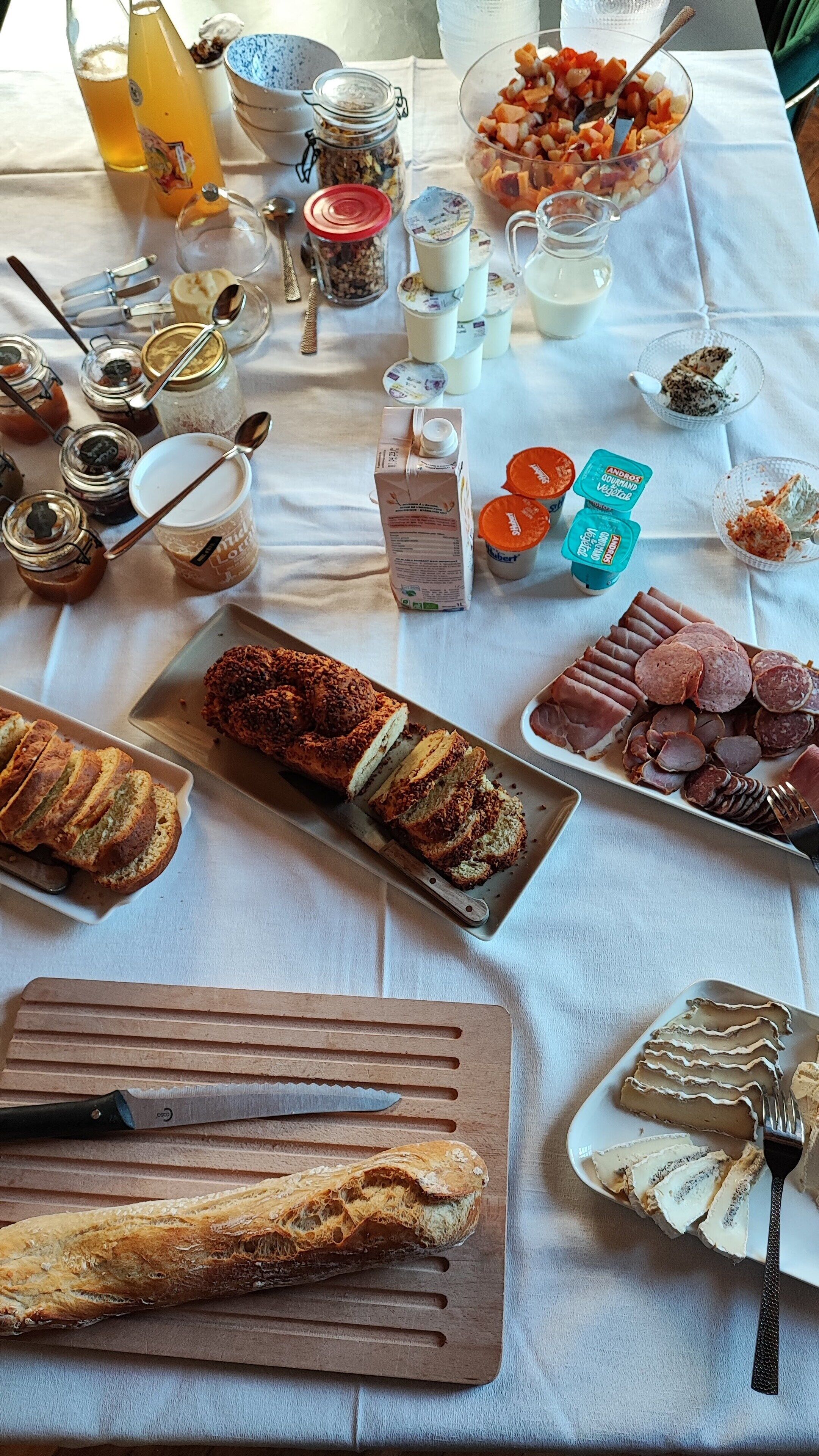 Une table où sont disposés divers aliments, notamment des tranches de pain, des pâtisseries et une variété de condiments.