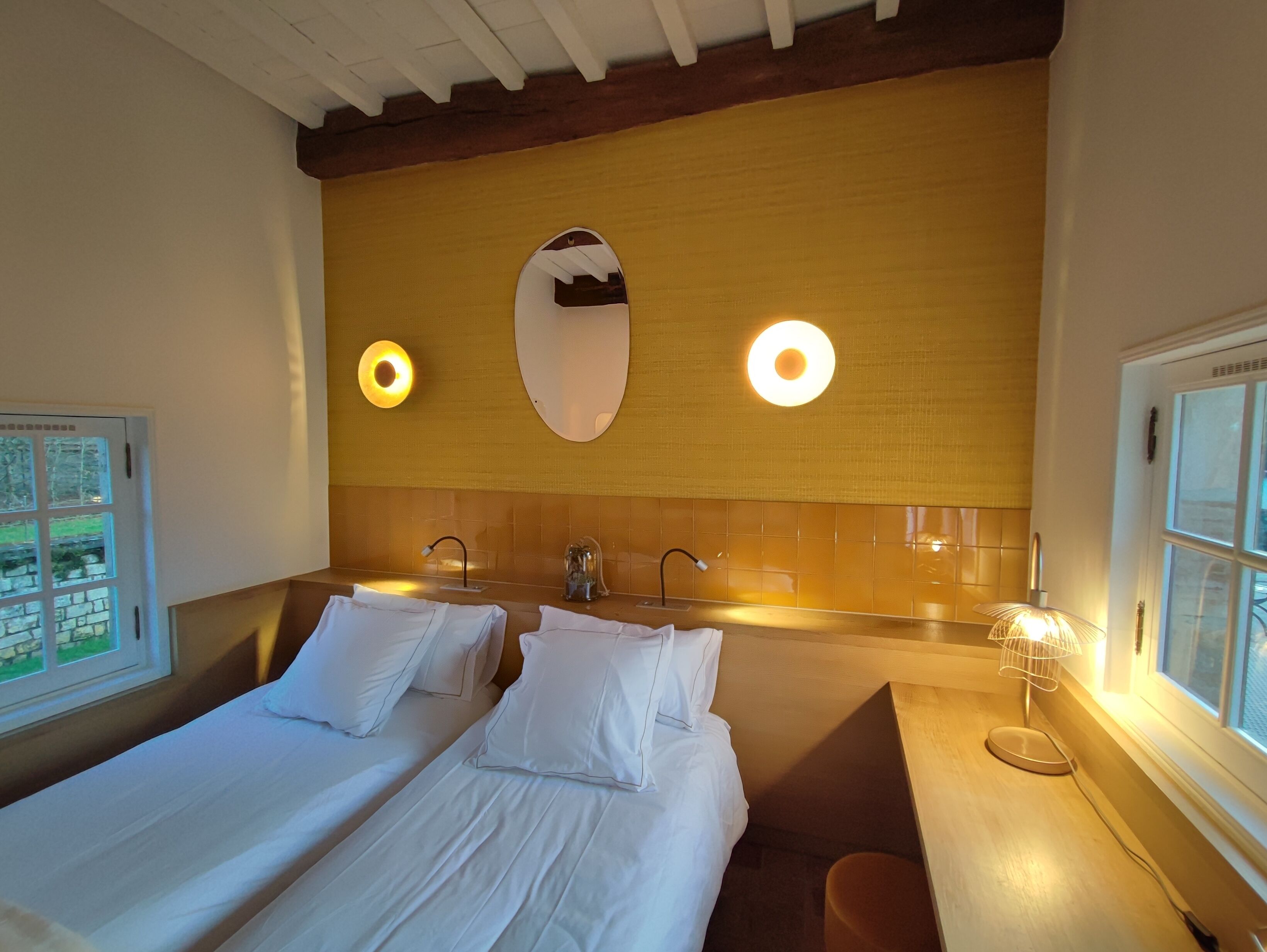 Habitación de hotel con dos camas, un espejo grande y una ventana.