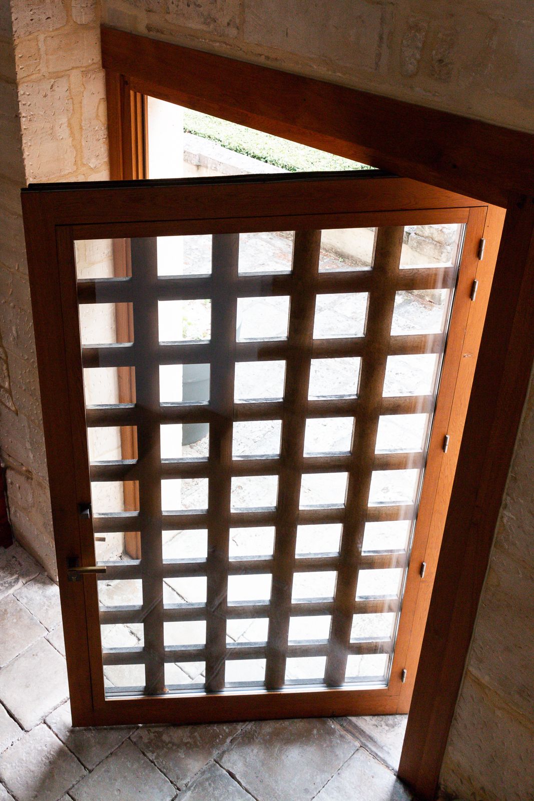 A wooden door with a grid pattern, leading to an outdoor area.