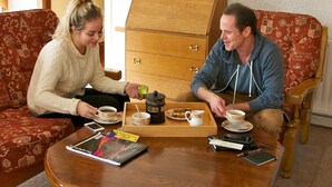 A room with a wooden cabinet, a coffee table with a tray of food and drinks, and a sofa with patterned cushions. - Ach na Sheen Guest House (Tipperary)