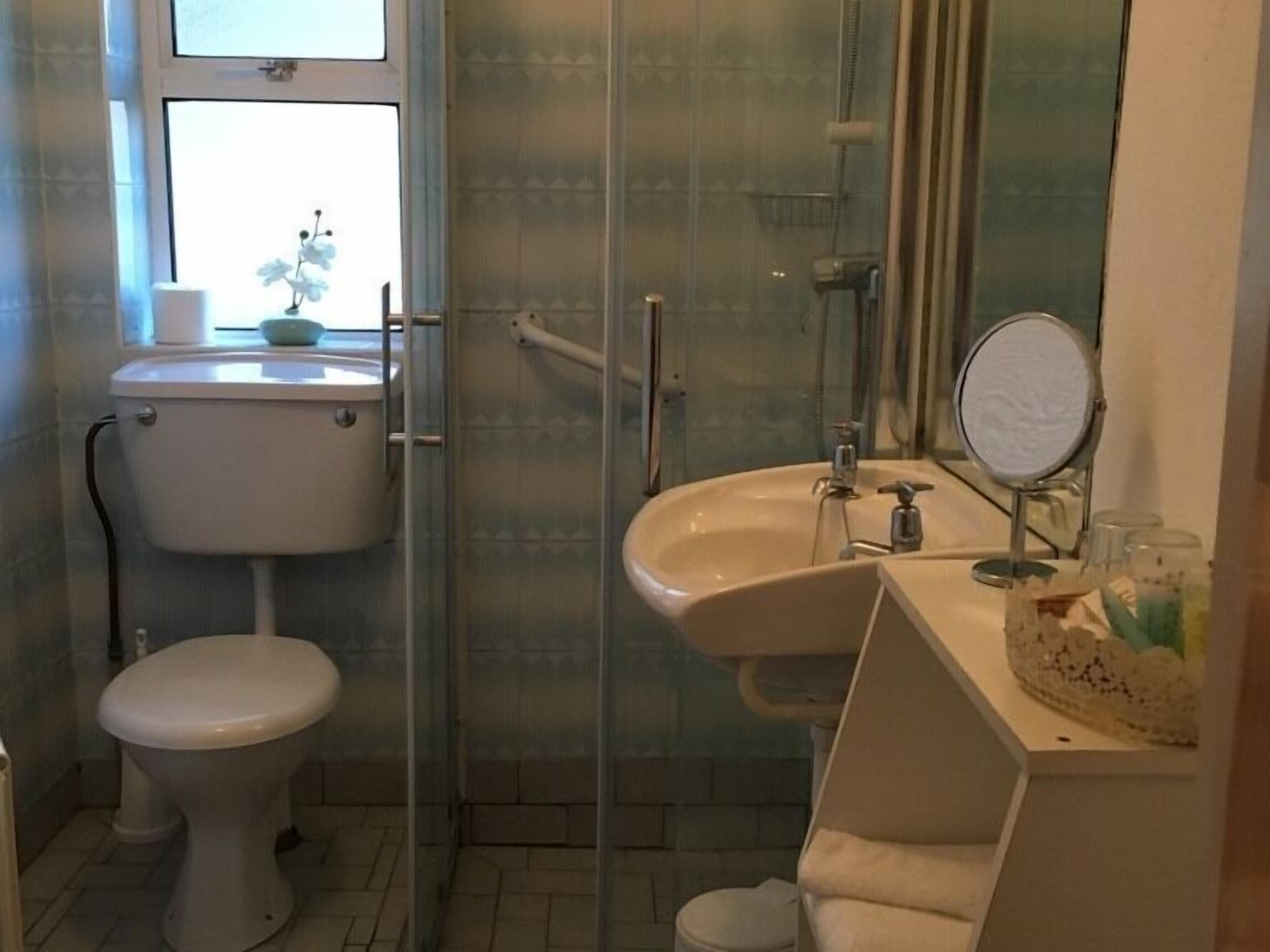 Baño con inodoro, lavabo y cabina de ducha de vidrio.