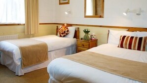 A hotel room with two single beds, a wooden headboard, a nightstand with a vase of flowers, and a window with curtains. - Ach na Sheen Guest House (Tipperary)