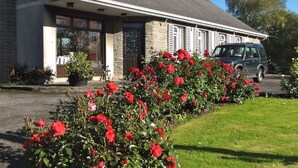 A building with a stone facade, a covered entrance, and a parked car in front. - Ach na Sheen Guest House (Tipperary)