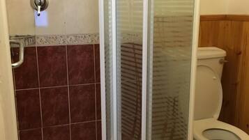 Un baño con cabina de ducha de vidrio, inodoro y paredes de azulejos.