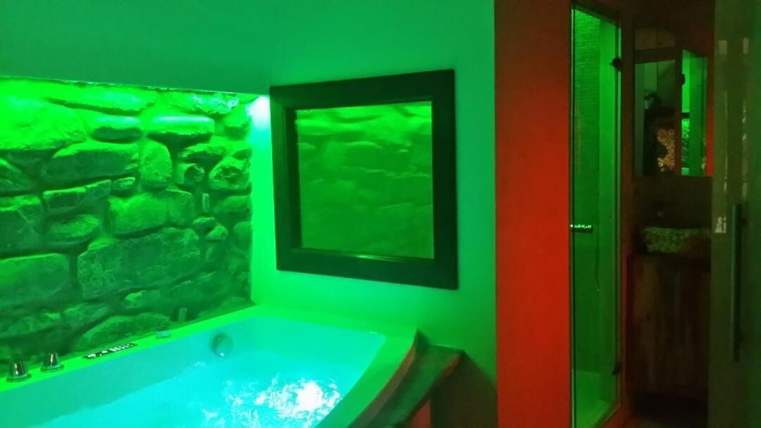 A bathroom with a stone wall, a framed picture, and a bathtub.