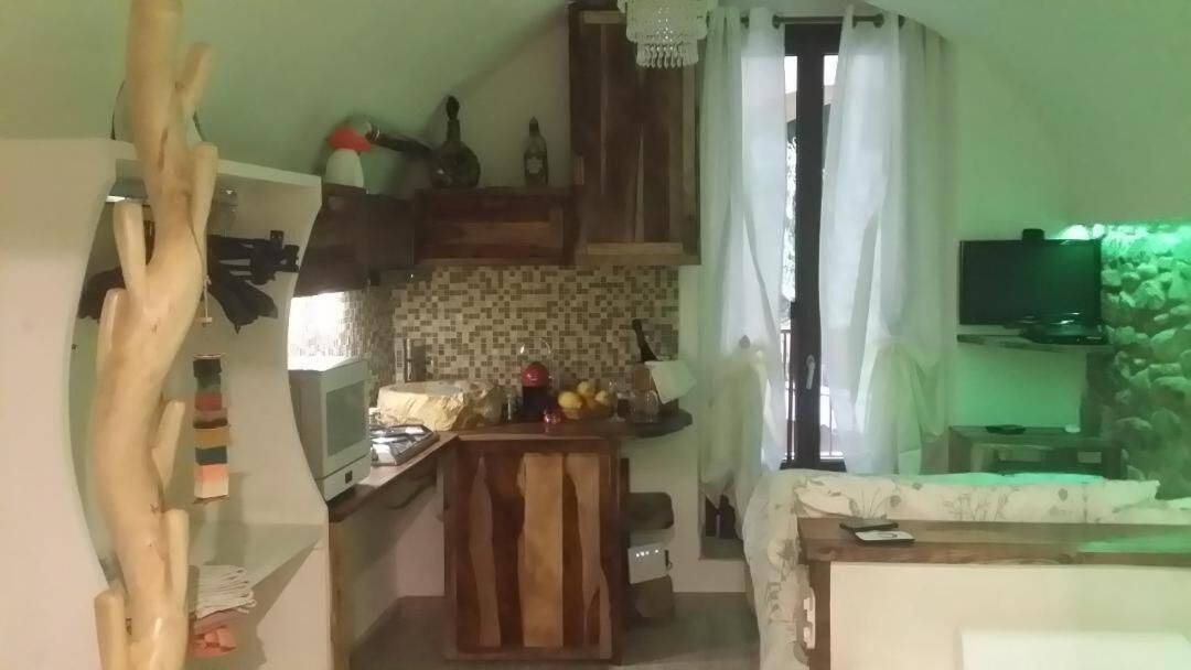 A compact kitchen with a wooden island, a microwave, and a television in the background.