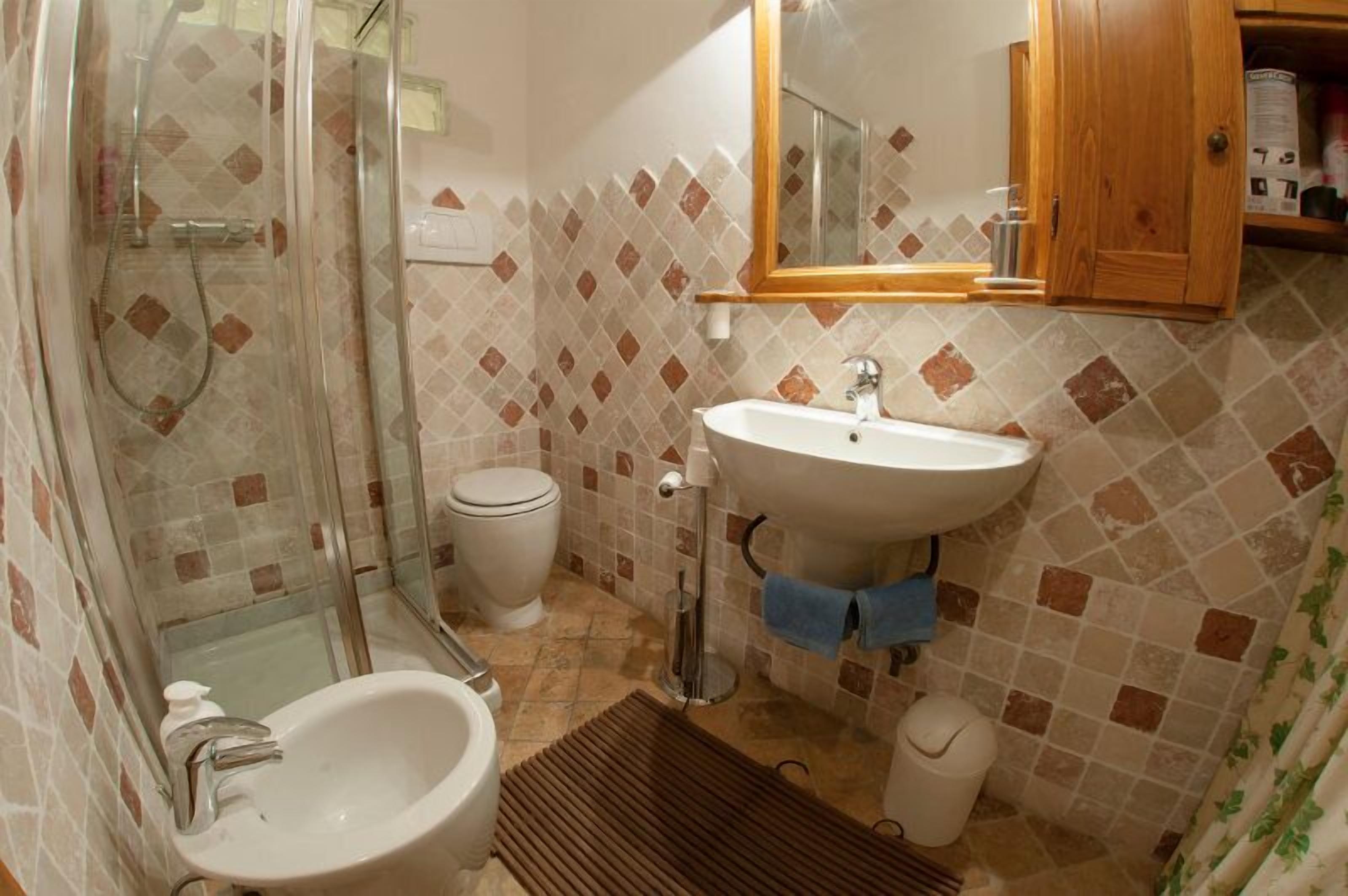 A bathroom with a glass-enclosed shower, a toilet, a sink, and a mirror above the sink.