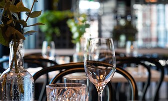 Una mesa de comedor con una botella de vino, una copa de vino y una copa de agua.