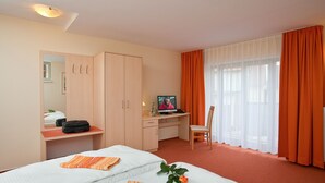 A hotel room with two beds, a desk with a computer, a chair, and a window with curtains. - Hotel Müritzperle (Waren (Müritz))